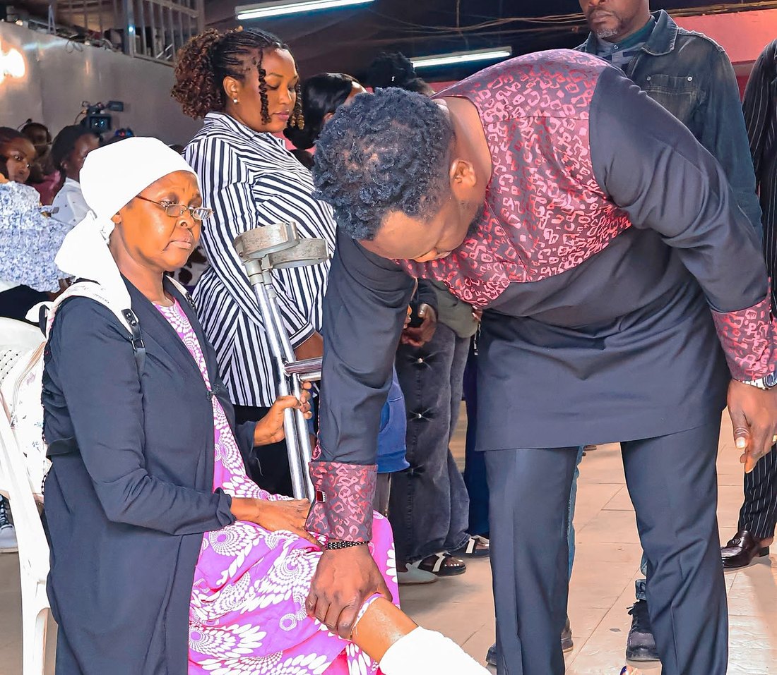 Rev B. Akama praying for a member during a service